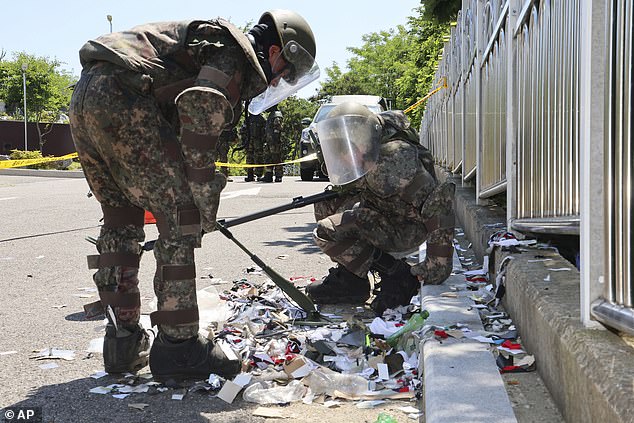 South Korean soldiers in protective gear sift through garbage from a balloon presumably sent by North Korea, in Incheon, South Korea, June 2, 2024.