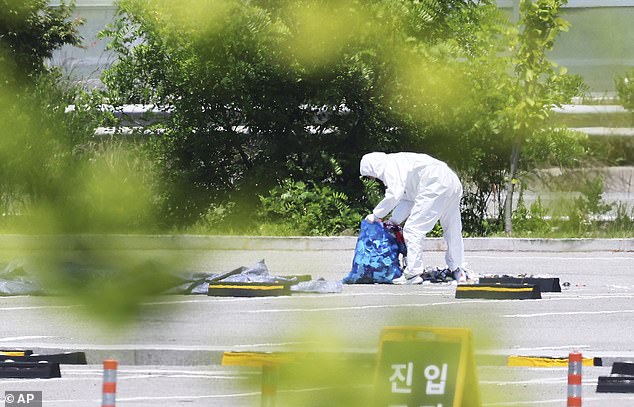 An officer in protective gear collects trash from a balloon presumably sent by North Korea, in Siheung, South Korea, Sunday, June 2, 2024.