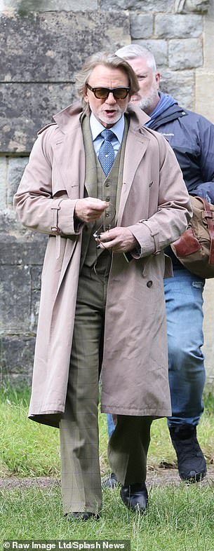 Daniel wore a long trench coat with a plaid three-piece suit underneath.