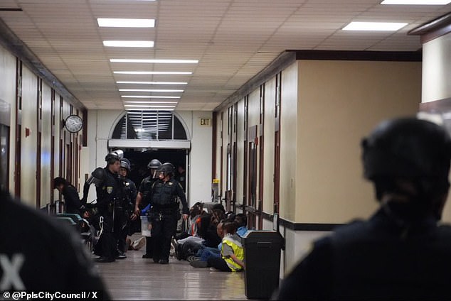 Protesters sit on the ground after being arrested, while waiting to be served with citations.