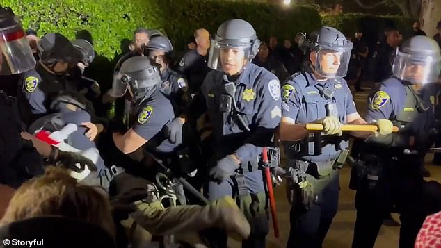 The police begin to push back a line of protesters carrying wooden shields.