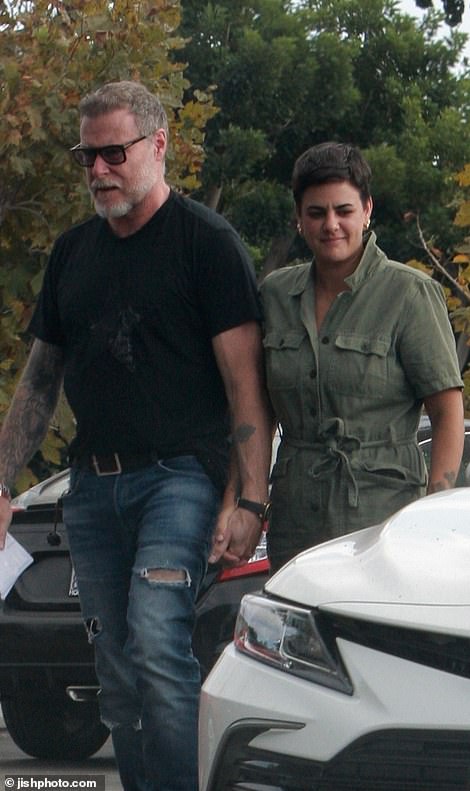 The 56-year-old was photographed holding the pixie-cut brunette's hand while clutching a stack of envelopes as they headed to the West Valley Department of Social Services office in Chatsworth.