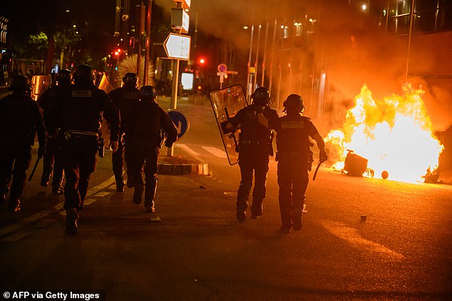 The far-right Freedom Party narrowly won the country's European Parliament elections for the first time. (Police walk past burning rubbish during an 'anti-fascist demonstration' following the results of the European elections, in Toulouse)