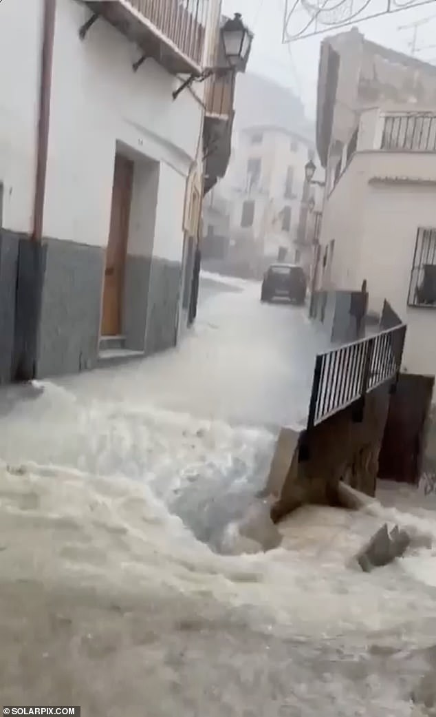 Water is seen flowing down a street in Murcia on Monday amid the storms