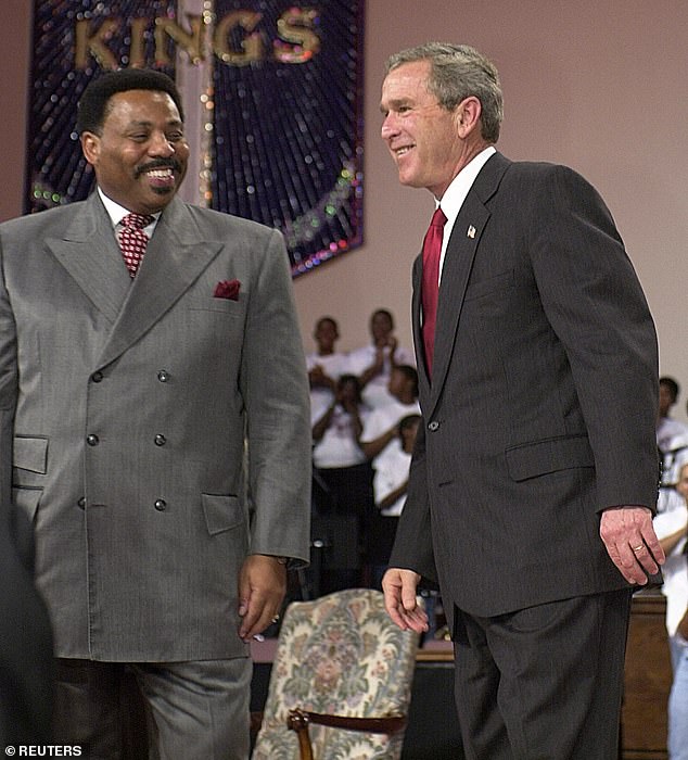 President George W. Bush listens to applause with Pastor Tony Evans at the dedication of the Oak Cliff Bible Fellowship Youth Education Center, October 29, 2003 in Dallas, Texas