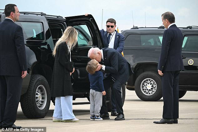 President Joe Biden kisses his grandson, baby Beau, son of Hunter Biden (right) and his wife Melissa Cohen (left)