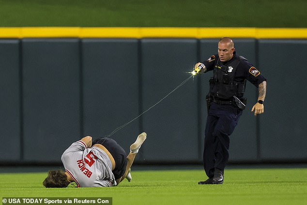 A police officer tasers a Cincinnati Reds fan after the fan ran onto the field Wednesday.