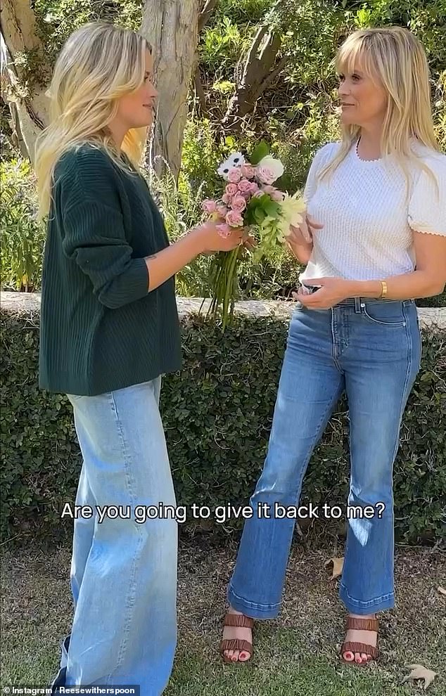 The producer and Ava pass a bouquet of flowers to each other.