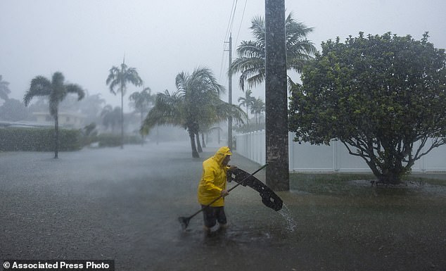 A man works to clear debris from a flooded street as heavy rain falls over parts of South Florida on Wednesday, June 12, 2024, in Hollywood, Florida.