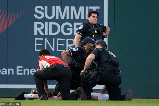 Three police officers and a security guard try to suppress a climate change protester