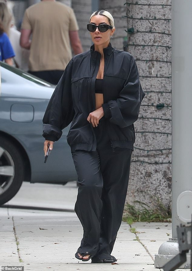 The Kardashian star was notably dressed in baggy black sweatpants, a windbreaker jacket, and sandals.