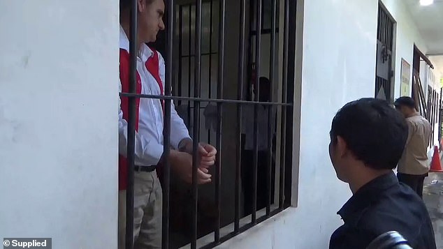 The father of two, wearing a white shirt, tan chinos and a red prison vest, did not answer questions from waiting reporters and hid his face in the corner of a holding cell.