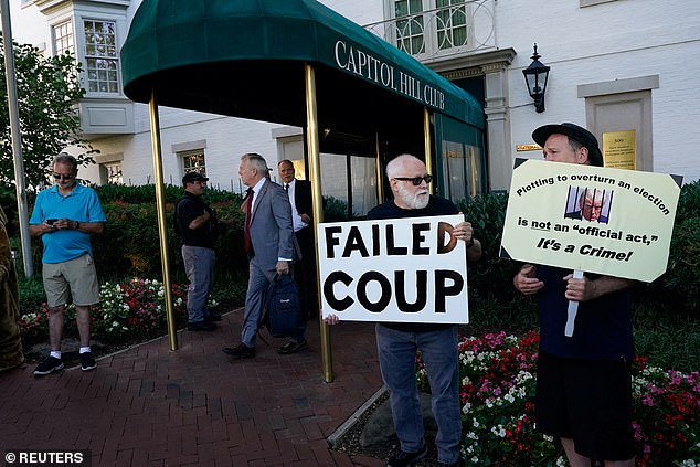 People hold signs outside the Capitol Hill Club before a meeting with House Republicans and Trump.