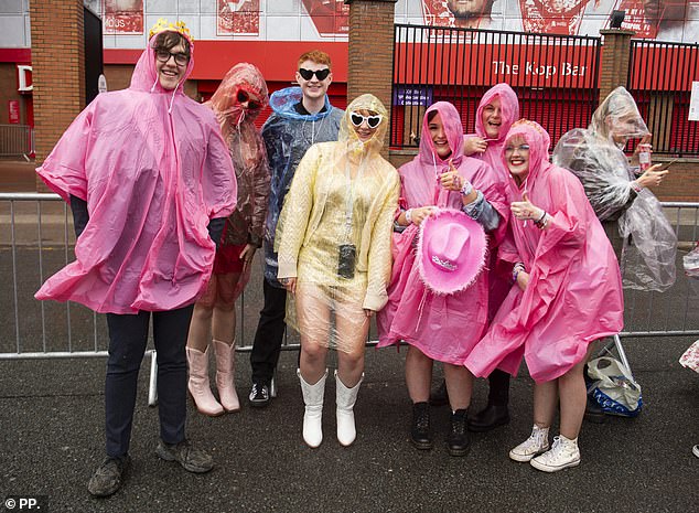 Poncho-wearing Swifties flocked to Anfield stadium dressed in sequins, feather boas and cowboy hats as they counted down the hours (pictured)