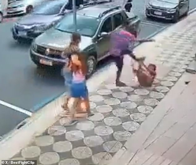 A man kicks a woman who is lying on the ground after she punches a young woman in the face without provocation