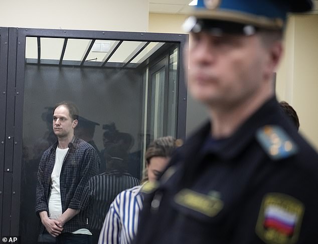 Wall Street Journal reporter Evan Gershkovich, left, stands in a glass cage in a courtroom at the First Court of Appeals of General Jurisdiction in Moscow.