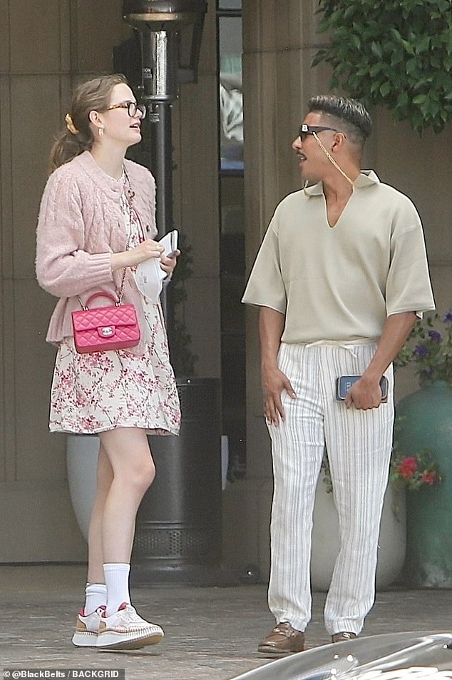 Violet was seen outside wearing a pink sweater, dress and sneakers with a padded bag hanging from her body.