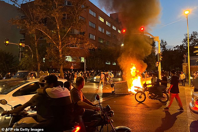 Iranian protesters burn a barricade during a protest for Mahsa Amini, a woman who died in custody after being arrested by the republic's 'morality police', in Tehran, September 2022.