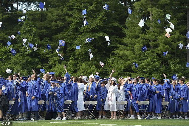 Graduates of Newtown High School's Class of 2024 throw their caps in the air as they conclude their graduation ceremony in Newtown on Wednesday. 60 graduates were among those who survived the Sandy Hook school shooting in 2012. The names of the 20 students killed were read aloud in a moving tribute.