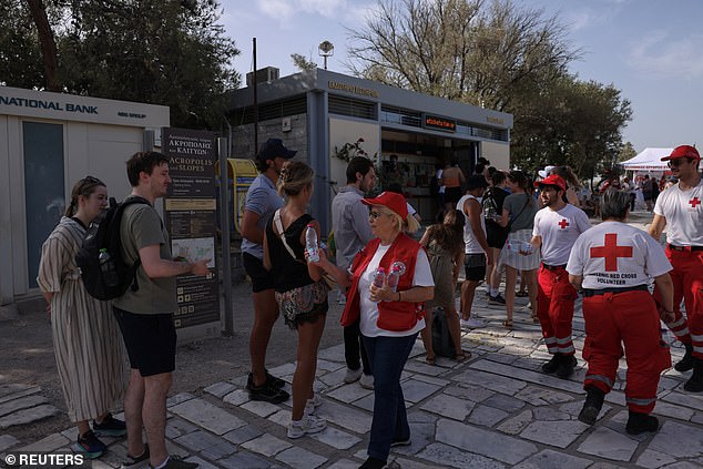 Members of the Hellenic Red Cross hand out bottles of water to tourists visiting the Acropolis