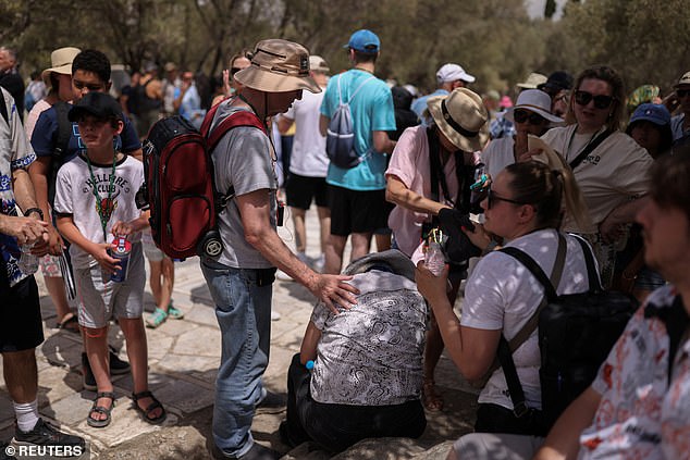 A woman receives help outside the Acropolis hill archaeological site after feeling unwell