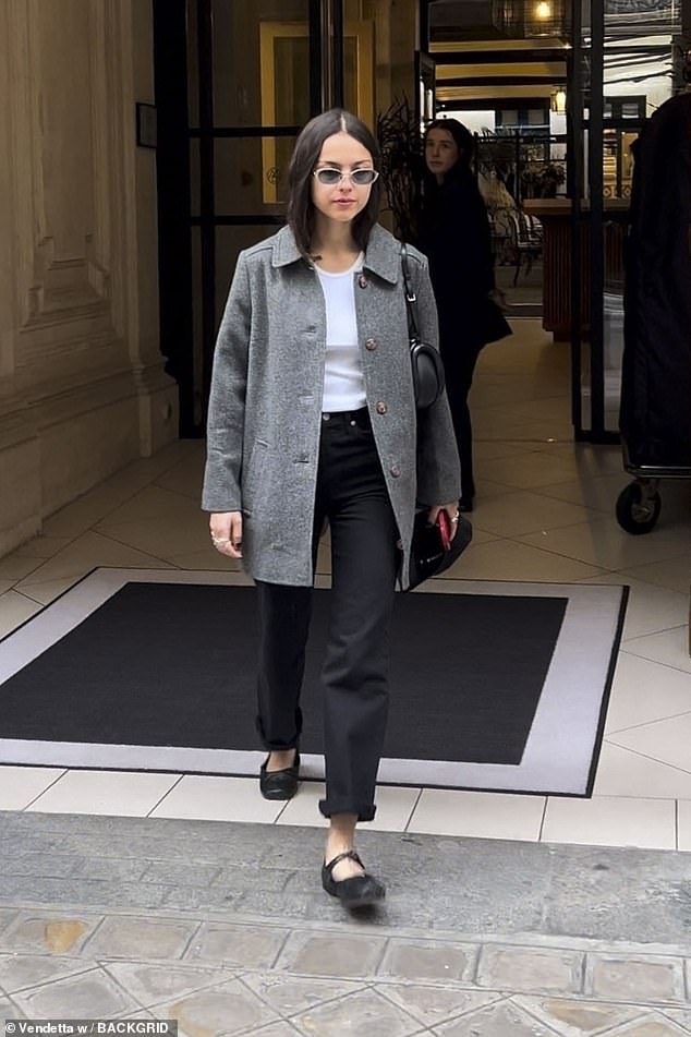 While in the City of Love, the 21-year-old pop star, who is dating English actor Louis Partridge, rocked a structured gray coat with silver buttons over a white blouse and a pair of short black pants.