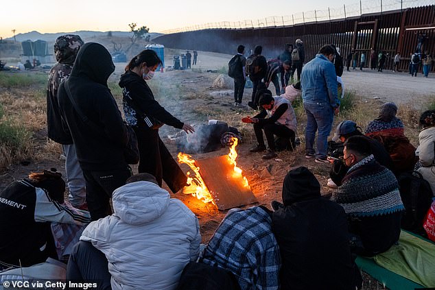 Migrants sit by a makeshift fire to warm themselves after crossing into the United States from Mexico in Jacumba Hot Springs, California.