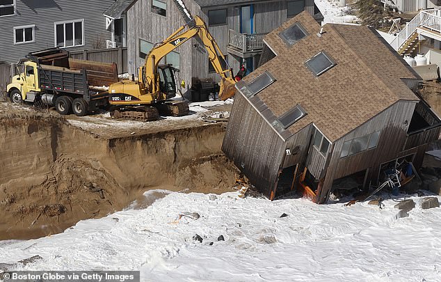 Construction crews prepare to tear down a home that fell off its foundation after yesterday's winter storm eroded the shoreline on Plum Island.