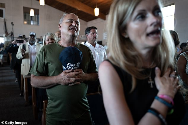 Guests listen to the national anthem before the start of a panel discussion with Republican presidential candidate and former President Donald Trump at Church 180.