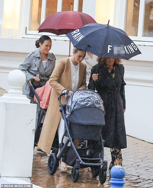 Simone, seen pushing a stroller, looked effortlessly chic in a long beige coat over a white dress.