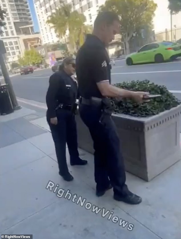 An LAPD police officer picked up the gun from the ground and inspected it before removing the magazine from the gun that appeared to be loaded.