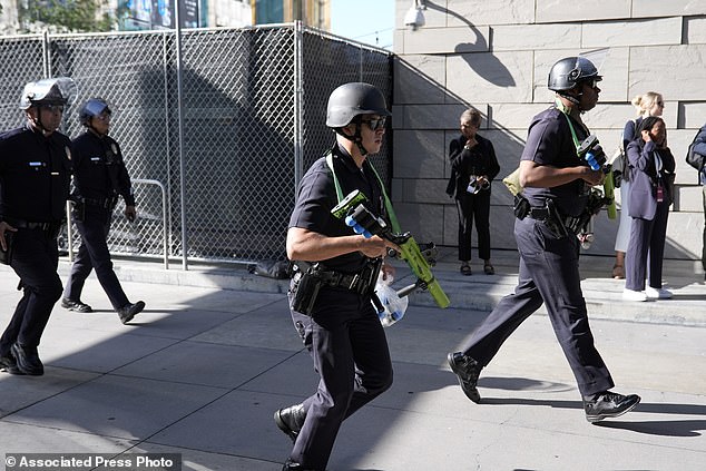 Law enforcement officers carrying less-lethal munitions respond to protesters near the campaign event with President Joe Biden in front of the Peacock Theater on Saturday in Los Angeles.