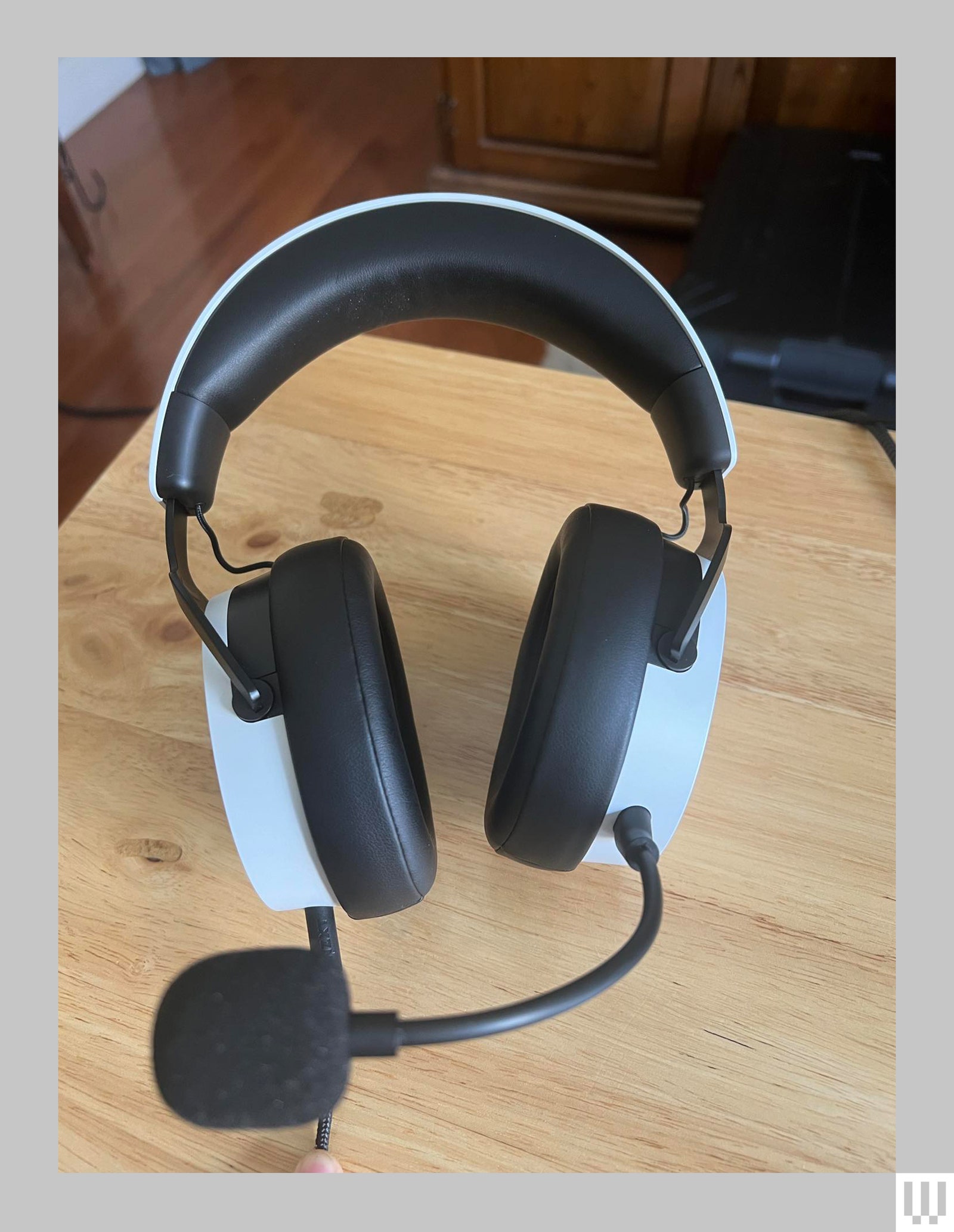 Overhead view of black and white headphones with microphone attached on a wooden surface