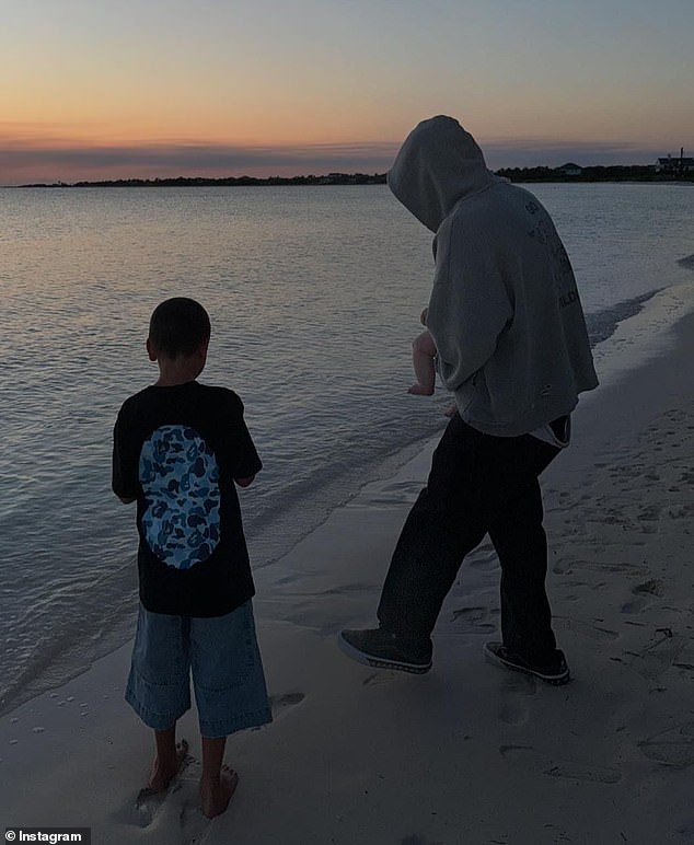 Another beachside snap showed the baby's legs dangling as Travis held him on the shore as the sun set.