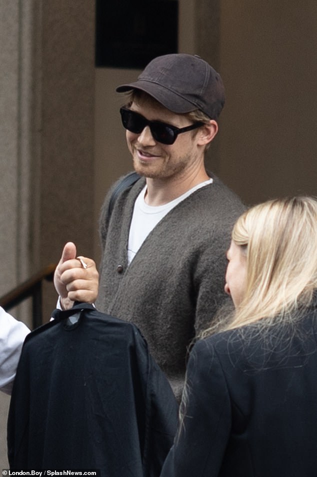 She was all smiles upon her arrival in Italy's fashion capital, opting for a casual oversized cardigan and a plain white T-shirt.