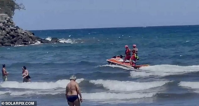 Lifeguards are seen patrolling a beach amid a series of shark sightings, forcing tourists to get out of the water.