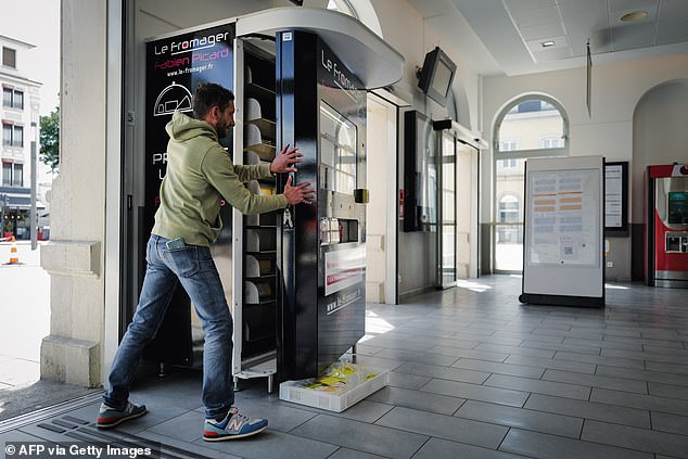 Cheese dispensers are the latest in a trend of machines selling pizzas, oysters, muscles, cold cuts and fresh bread (pictured: cheesemonger Fabien Picard fills his cheese vending machine at a train station in France)