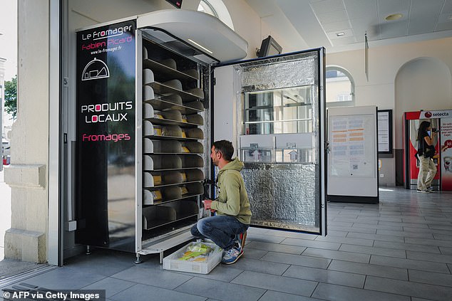 The automatic dispensers are refrigerated, protecting the surrounding area from wafting odors (pictured: cheesemonger Fabien Picard fills his cheese vending machine in Bourg en Bresse, eastern France).