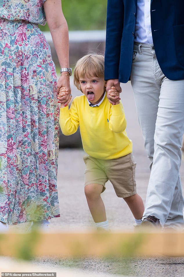 The young Swedish prince showed his cheeky side as he stuck out his tongue while his parents helped him.