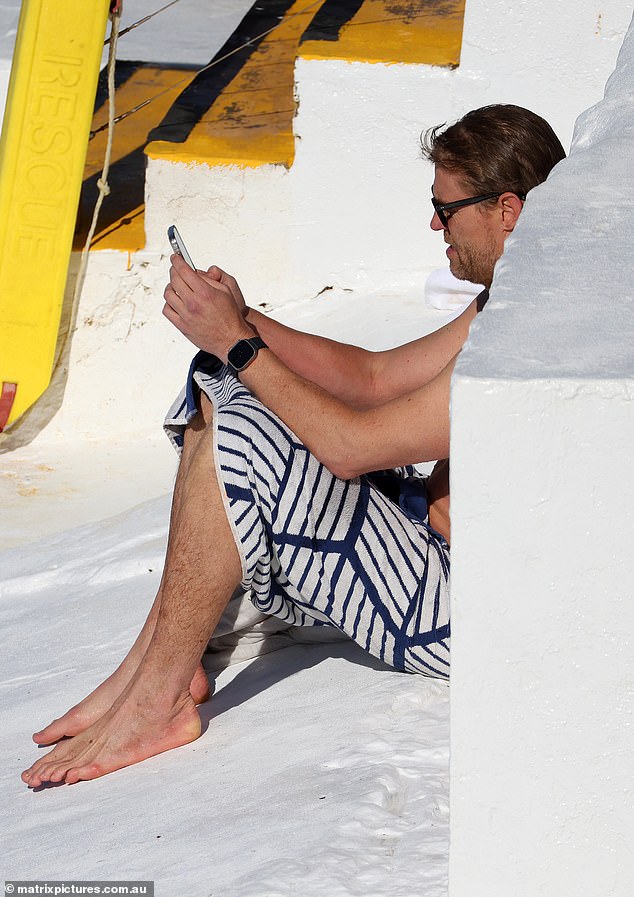 After the refreshing dip, Chris dried off with a black and white beach towel before wrapping it around his body and sitting down to check his iPhone.