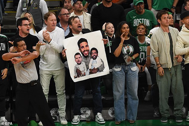 A Celtics fan holds up a photo of Tatum, Doncic and Irving that helps describe the series.