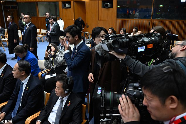 Two Chinese embassy officials (center) stand between the cameras and Lei (sitting behind them, not visible)