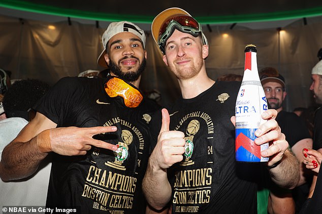 Sam Hauser (right) holds a beer aloft with Tatum as the Celtics kick off a long party.