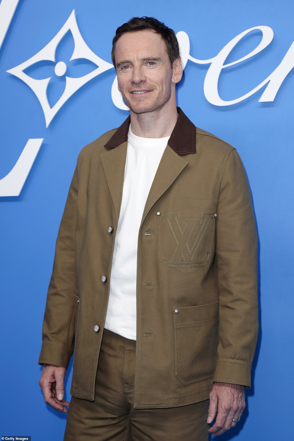 Michael Fassbender, 47, flashed a smile while sporting a brown and slightly Louis Vuitton ensemble consisting of a jacket and pants.