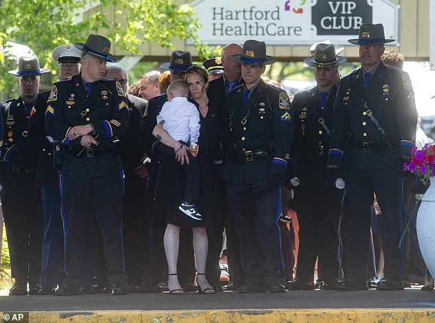 Dominique Pelletier holds one of her children as the casket of her husband, Connecticut State Trooper Aaron Pelletier, is carried out of the Xfinity Theater following his funeral in Hartford, Connecticut, on Wednesday, June 5.