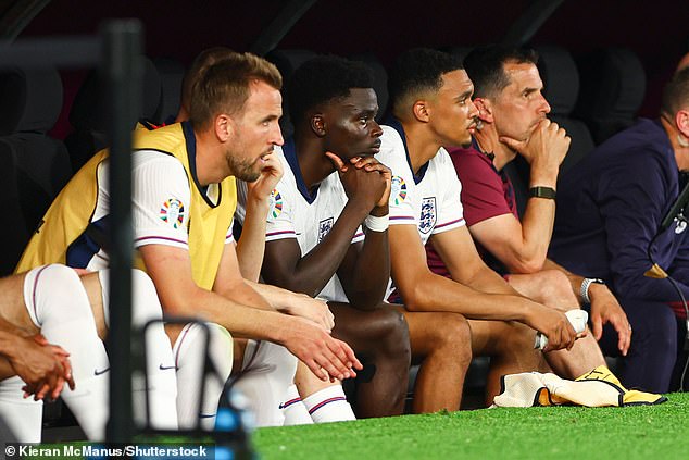 The Liverpool star (centre right) watches from the bench after being substituted against Denmark.