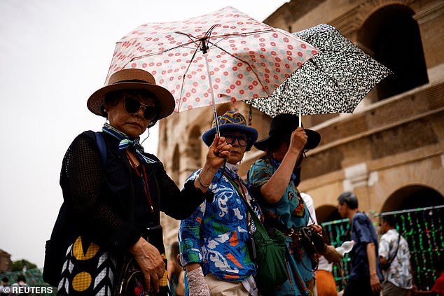 Tourists hold umbrellas to protect themselves from the sun as they walk near the Colosseum amid a heat wave in Rome.