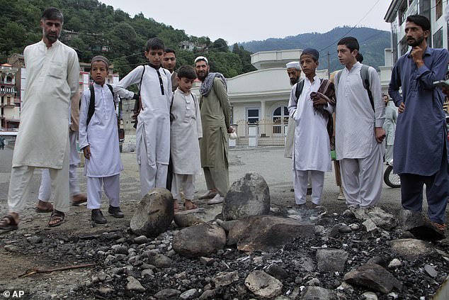 Local residents look at the site where a Muslim mob lynched and burned a man over blasphemy accusations