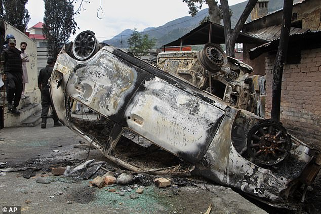 Police officers examine vehicles burned by a Muslim mob in an attack, in Madyan, Pakistan's Khyber Pakhtunkhwa province.