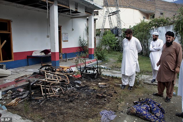 Plainclothes police officers examine furniture burned by the mob